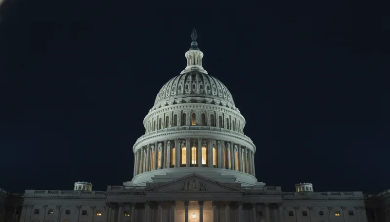 The Capitol dome stands illuminated against the night sky as a single window remains lit inside.